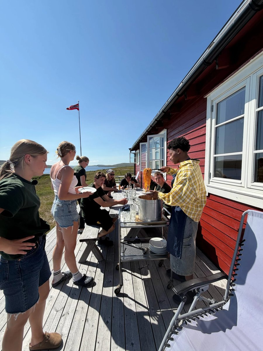 Venner samlet rundt et bord utenfor en rød hytte